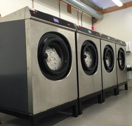 Rij van vier professionele wasmachines met wasgoed erin