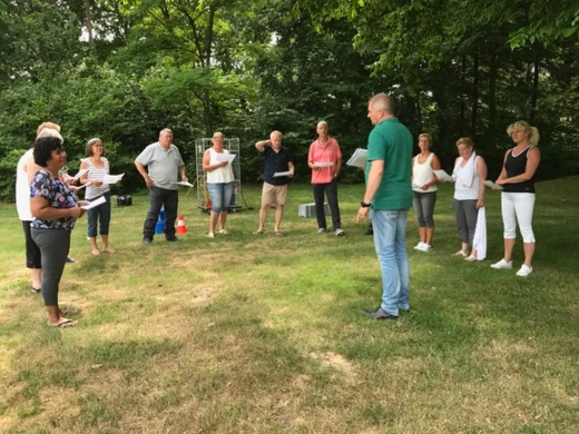 Groep mensen zingt buiten tijdens een workshop