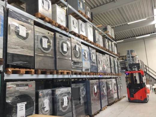 Stellingen met tweedehands wasmachines en drogers op pallets
