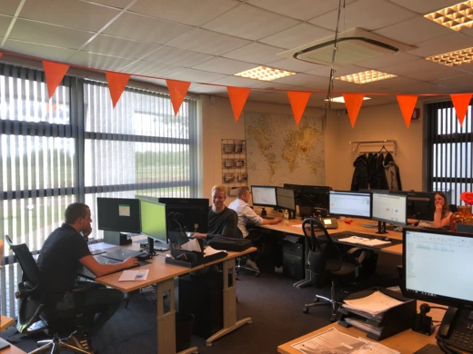 Kantoorruimte met bureaus, beeldschermen en oranje vlaggetjes