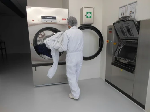 Medewerker in cleanroom-pak laadt een wasmachine in een cleanroom