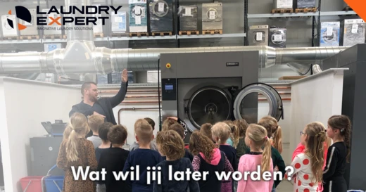 Medewerker Berto legt schoolkinderen een professionele wasmachine uit, met de tekst 'Wat wil jij later worden?'