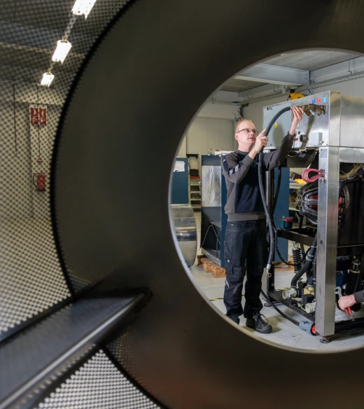 Technicus repareert het binnenwerk van een wasmachine door de trommelopening