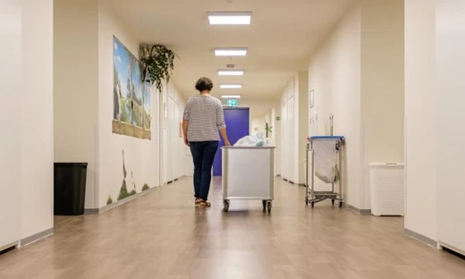 Medewerkster loopt met een wasgoedkar door een gang