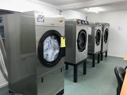 Rij industriële wasmachines en drogers met een label aan een deur
