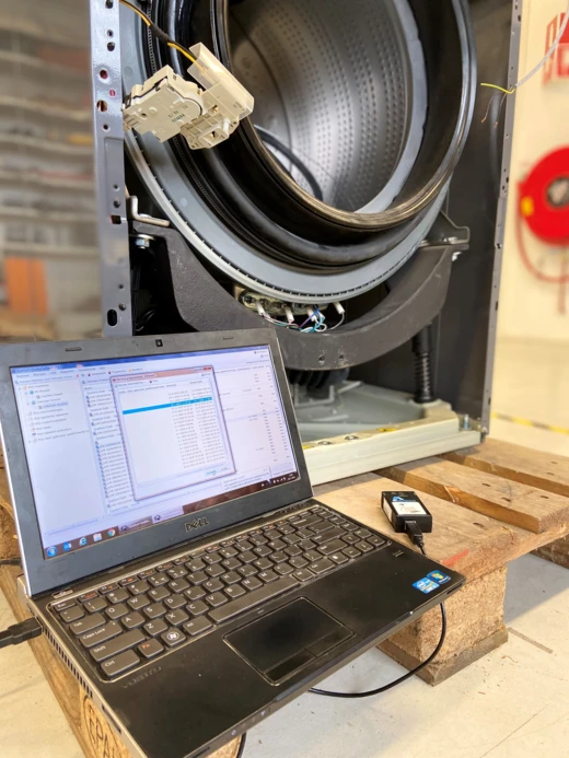 Opengewerkte wasmachinetrommel met een laptop voor diagnose