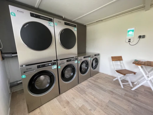 Wasserette-interieur met gestapelde wasmachines en drogers en een houten stoel