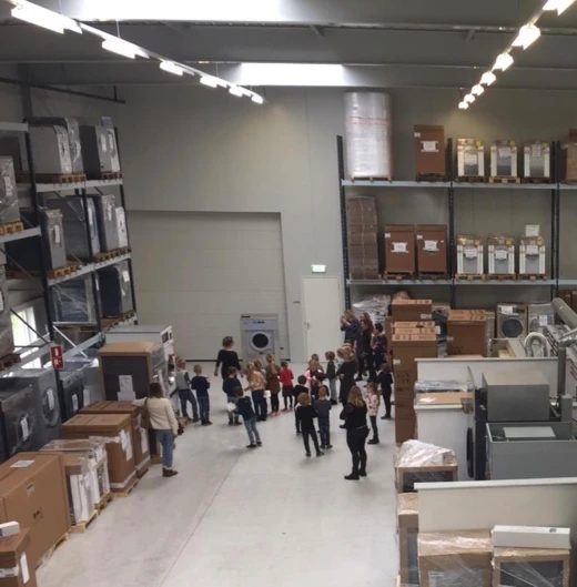 Bezoekers lopen rond in het magazijn tussen wasmachines