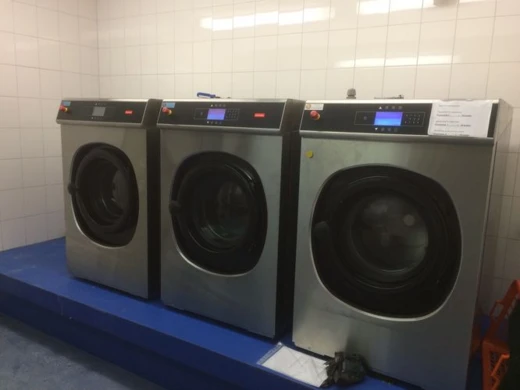 Drie professionele wasmachines in een wasserette