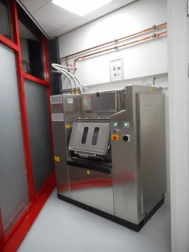 Barrièrewasmachine aan de vuile zijde van een wasserij