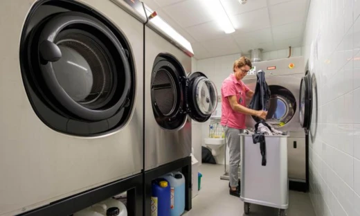 Medewerkster vult een professionele droger bij in een wasserette